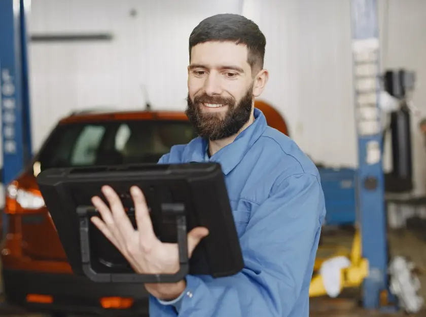 Mechanic using digital tablet to access workshop manual in auto repair garage