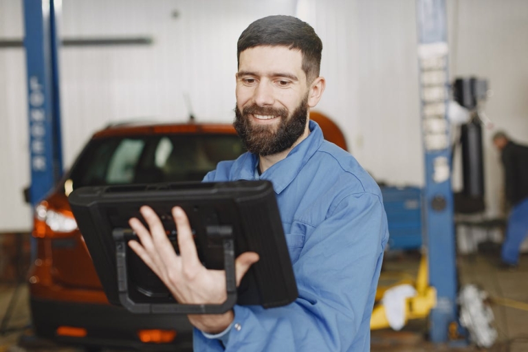 Mechanic using digital tablet to access workshop manual in auto repair garage